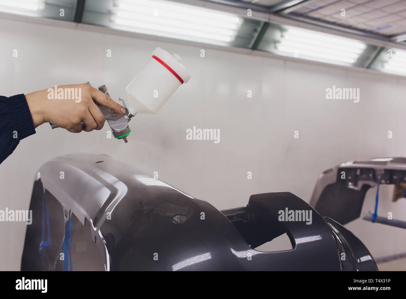 Worker Painting A Car Black Blank Parts In Special Garage Wearing