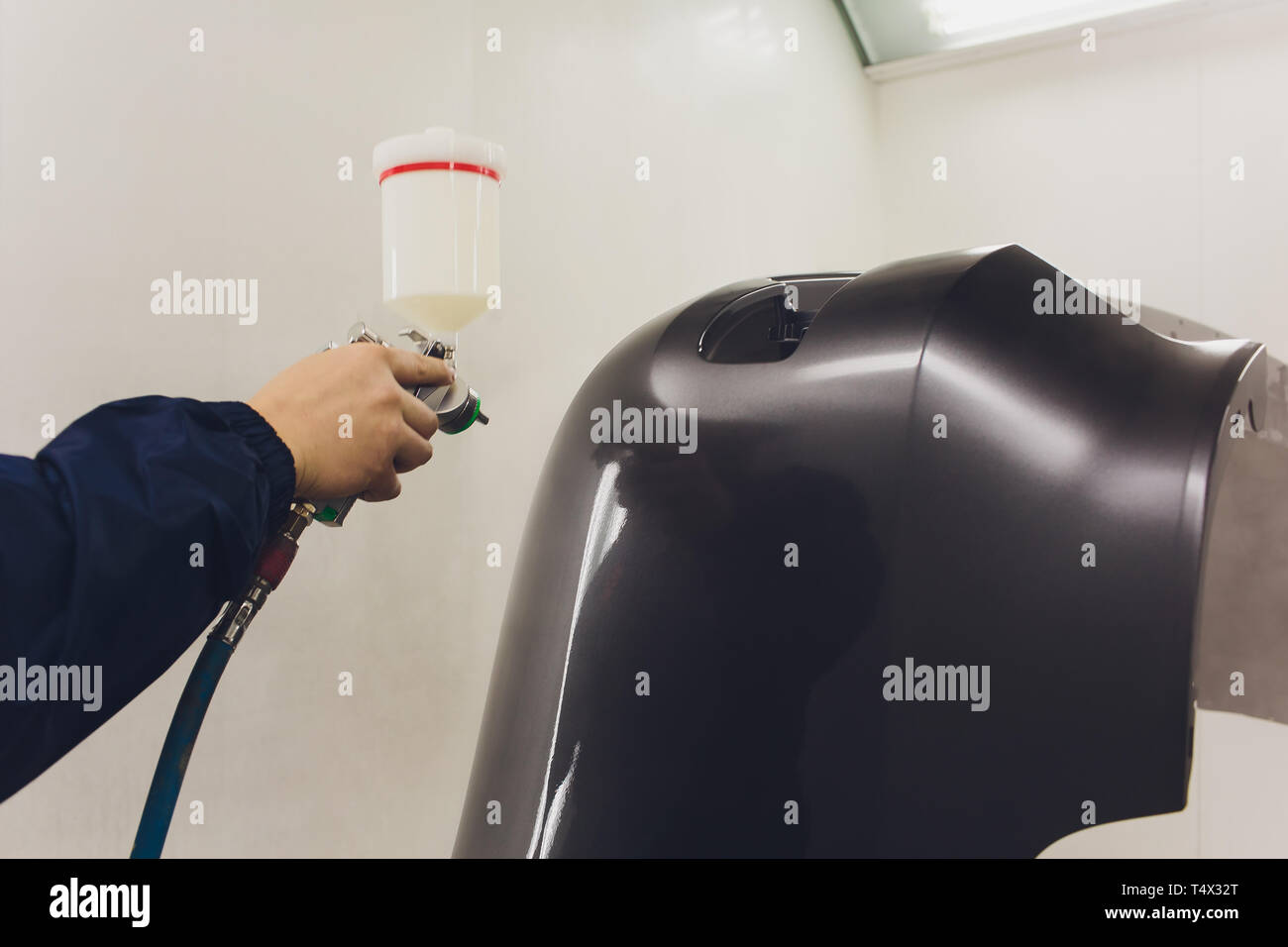 worker painting a car black blank parts in special garage, wearing