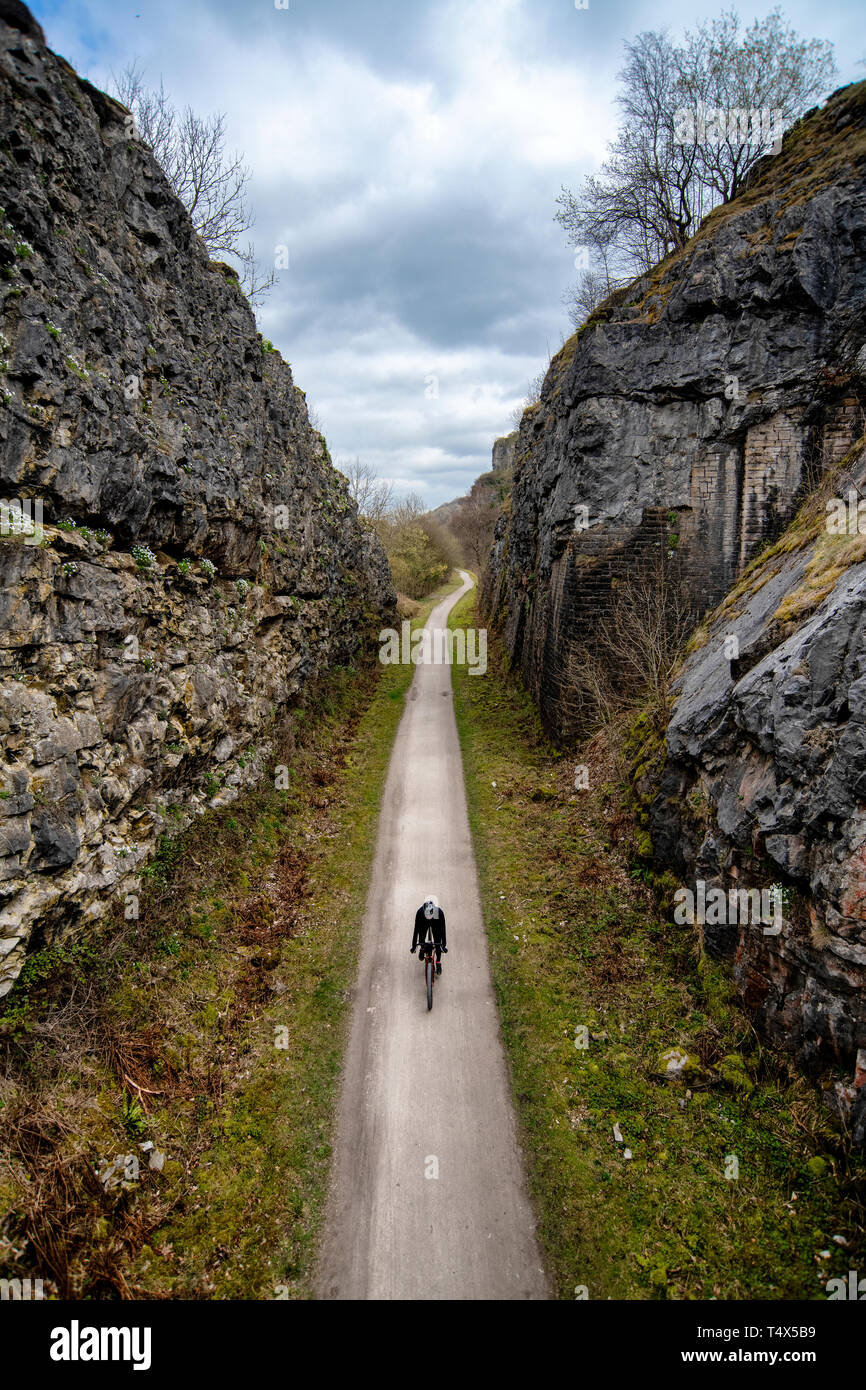 A man rides a bicycle through a cutting along the Monsal Trail in the Derbyshire Peak District. Stock Photo