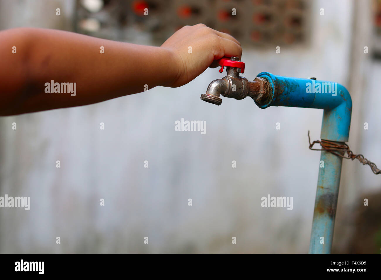 Young hands turning off an old rusty water tap for saving water save