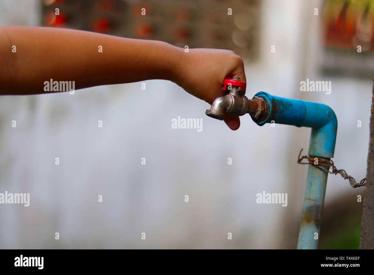 Young hands turning off an old rusty water tap for saving water save