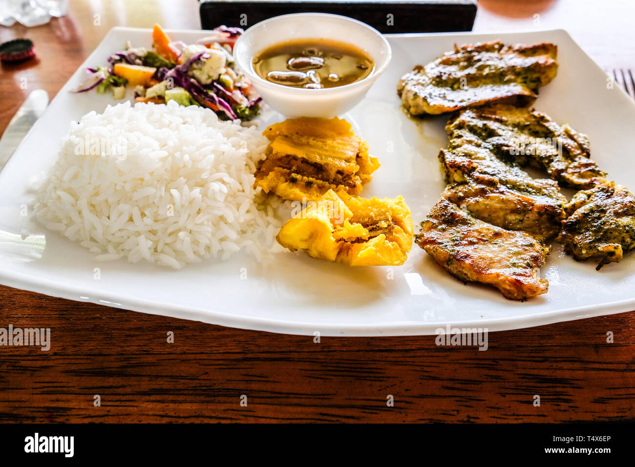 A plate of lunch combo with fried free range chicken, rice, bowl of
