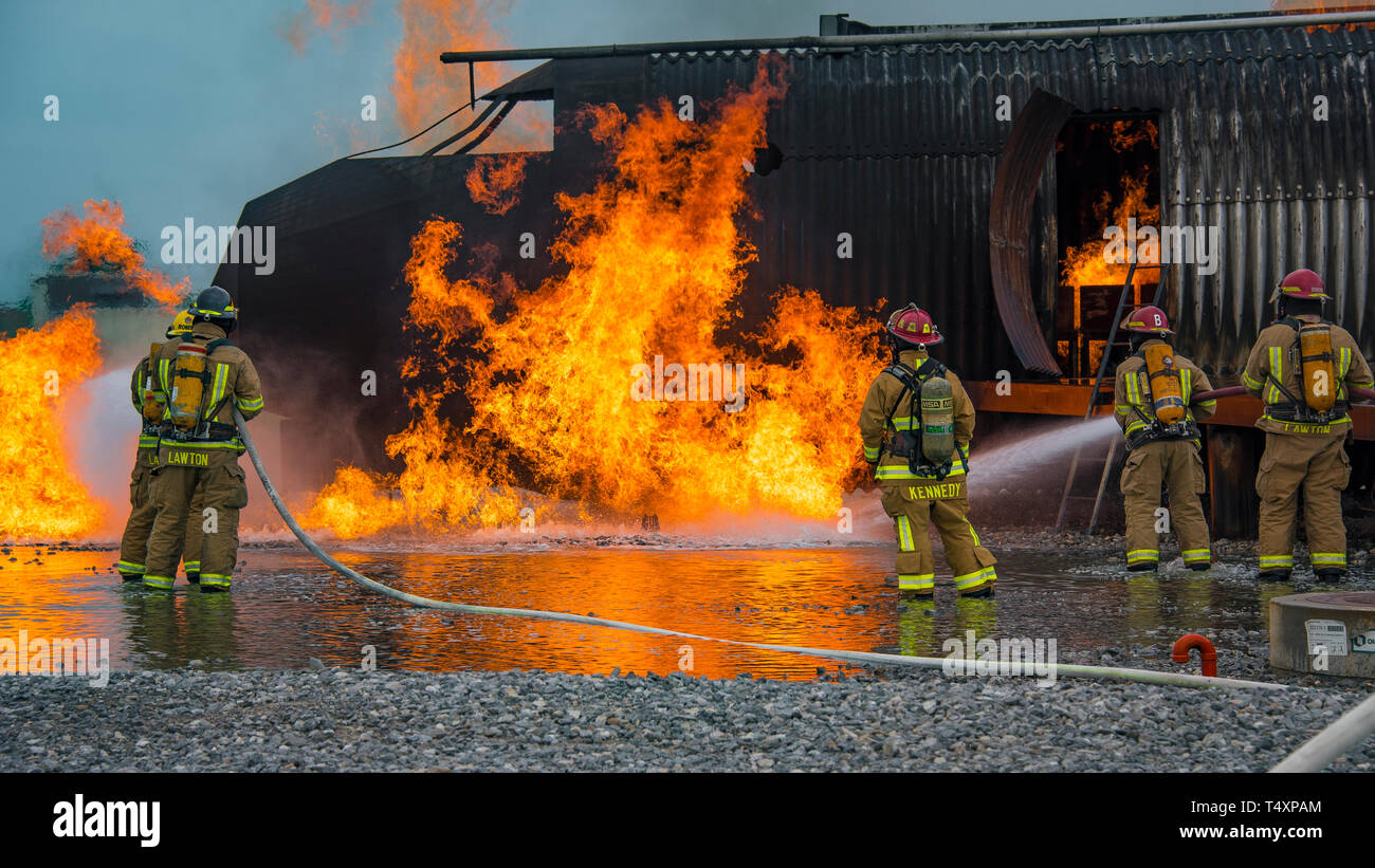 Firefighters work together to battle a blaze during a training exercise at Sheppard Air Force Base, Texas, April 17, 2019. Departments from Sheppard, Wichita Falls, Texas, and Lawton, Oklahoma, converged on the Sheppard AFB fire pit to practice different methods of combating an aircraft fire. (U.S. Air Force photo by John Ingle) Stock Photo