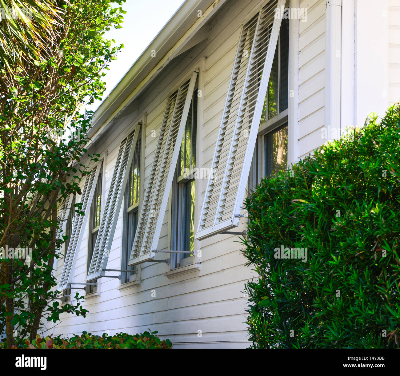 An exterior view of opened Bahama style storm shutters on the outside of an old white church in Boca Grande, FL, on the island of Gasparilla Stock Photo