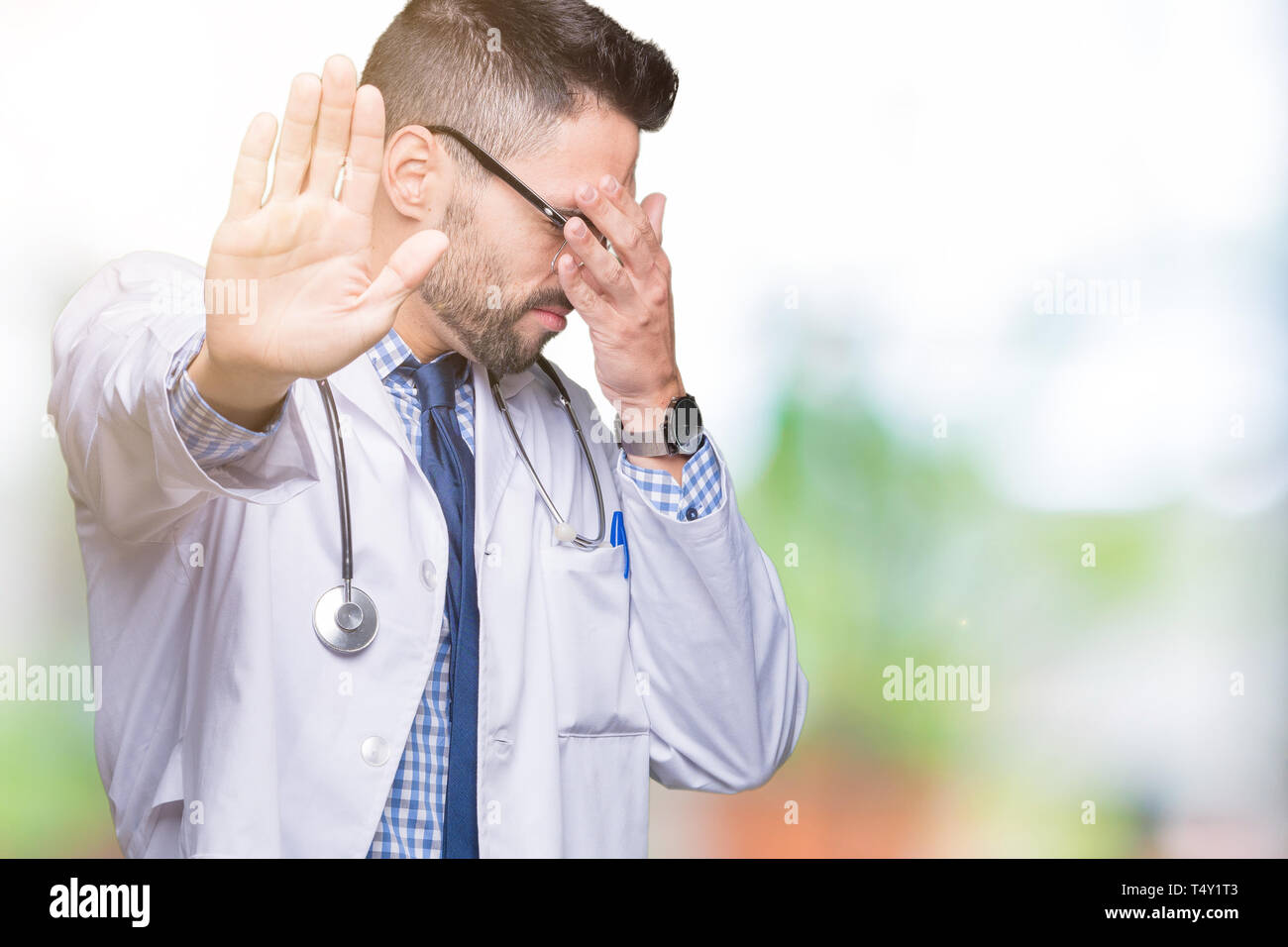 Handsome young doctor man over isolated background covering eyes with hands and doing stop gesture with sad and fear expression. Embarrassed and negat Stock Photo