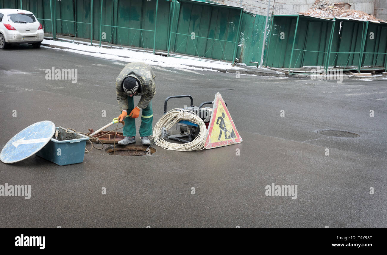 The employee opened the hatch on the street, started the power generator and lowered the electrical cable down to eliminate the emergency situation Stock Photo