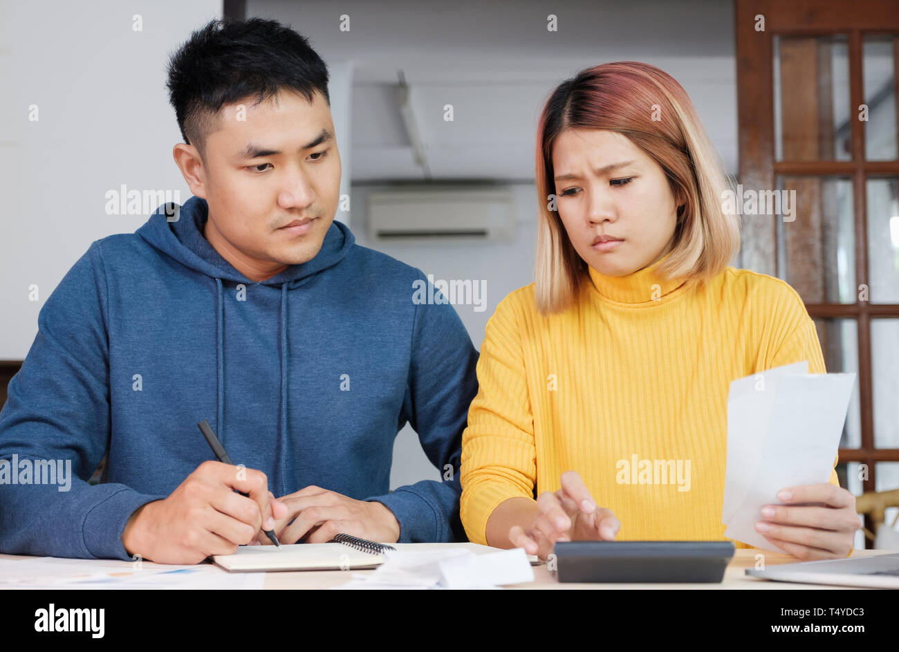 Stressed Asian couple serious calculate home financial bill budget on table in kitchen at new house Stock Photo