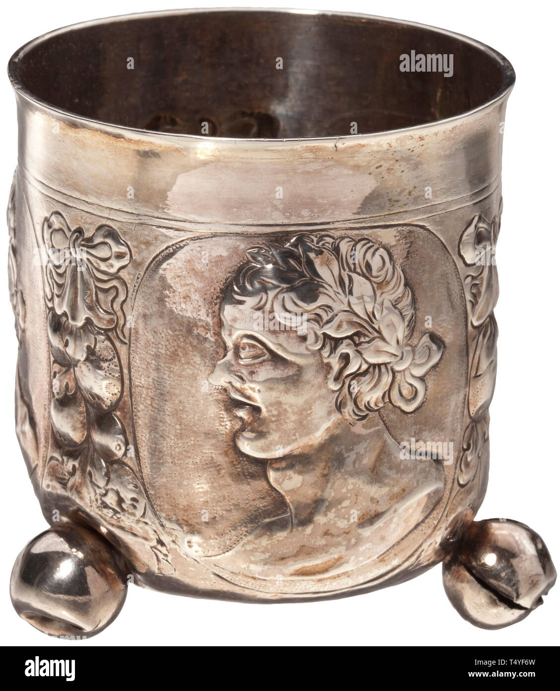 A Nuremberg silver goblet with ball feet Circa 1700. Cylindrical goblet on three ball feet. Slightly reinforced lip, the exterior with three antique-style portrait heads amid fruit festoons. The ball feet partially damaged, two with old repairs. Assayer´s mark on the bottom, Nuremberg city mark and master´s mark 'CW' with star. Beside it engraved owner´s monograms 'RHS' and 'RCL' with date '1700'. Height 8.5 cm, weight 82 g. Considerably improvable by restoration. historic, historical, handicrafts, handcraft, craft, object, objects, stills, clipp, Additional-Rights-Clearance-Info-Not-Available Stock Photo