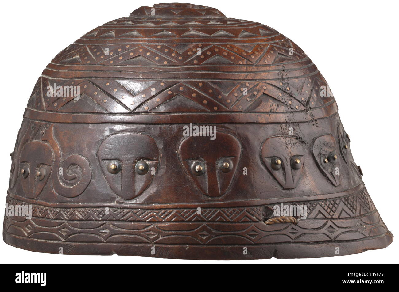 A carved wooden helmet, Chinese/Taiwanese, 19th century. One-piece helmet made from hardwood. The outside completely carved with stylised faces, geometrical decorations as well as a snake on the crown plate. Several continuous rows of inlaid copper and brass pins, some of them underlaid with horn discs. Two braided chin straps attached to the helmet. Diameter 20 cm. ++ historic, historical, China, Chinese, 19th century, Additional-Rights-Clearance-Info-Not-Available Stock Photo
