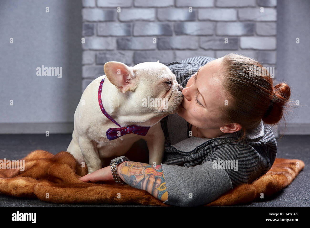 Young beautiful woman hugging her french bulldog puppy and kissing him ...