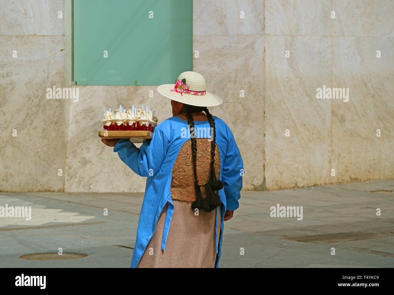 Back view of a Peruvian lady selling jelly sweets at the main square of Puno, Peru Stock Photo