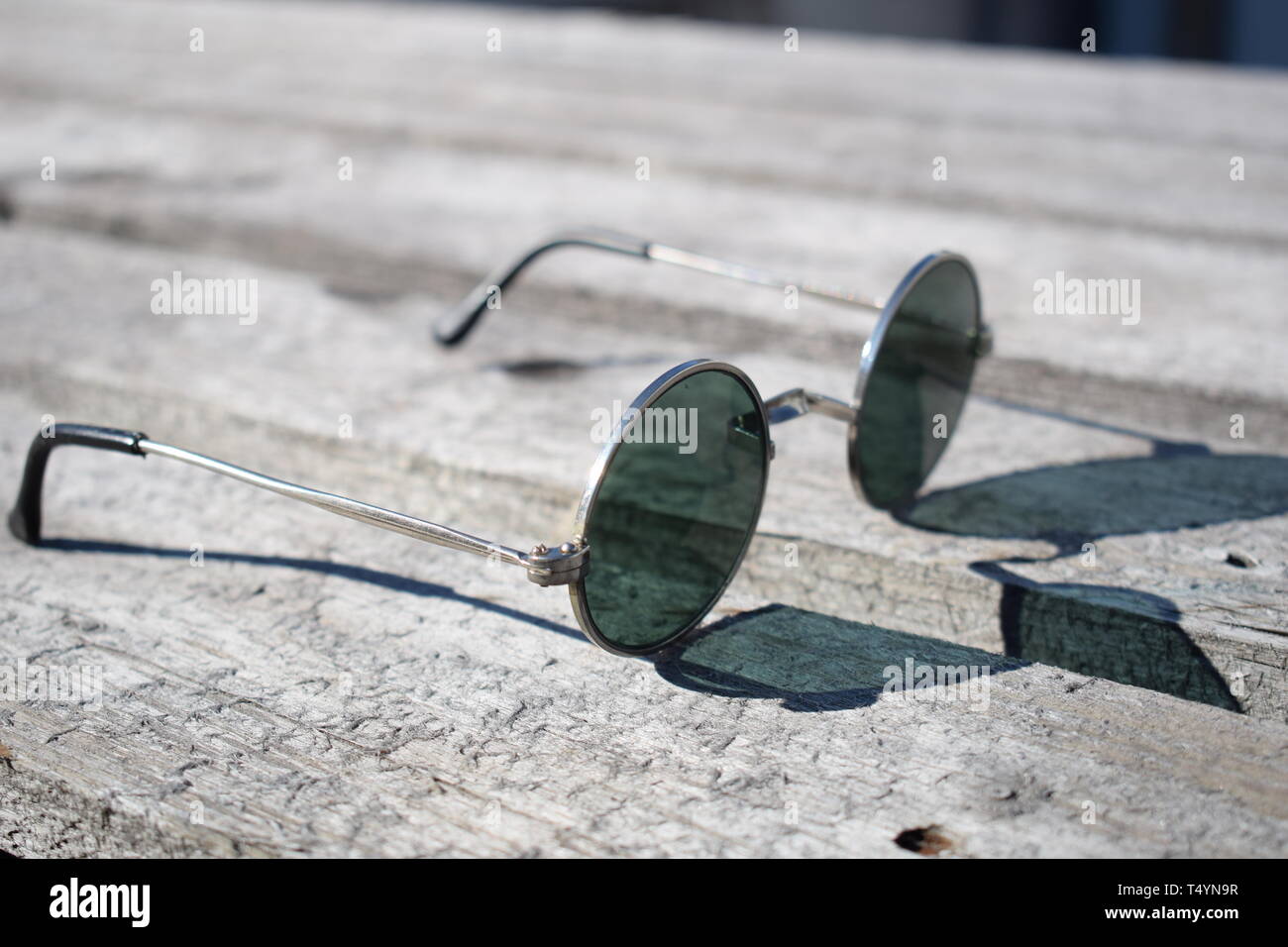 Summer concept. Sunglasses silver round with black lens, on a wooden  background Stock Photo - Alamy