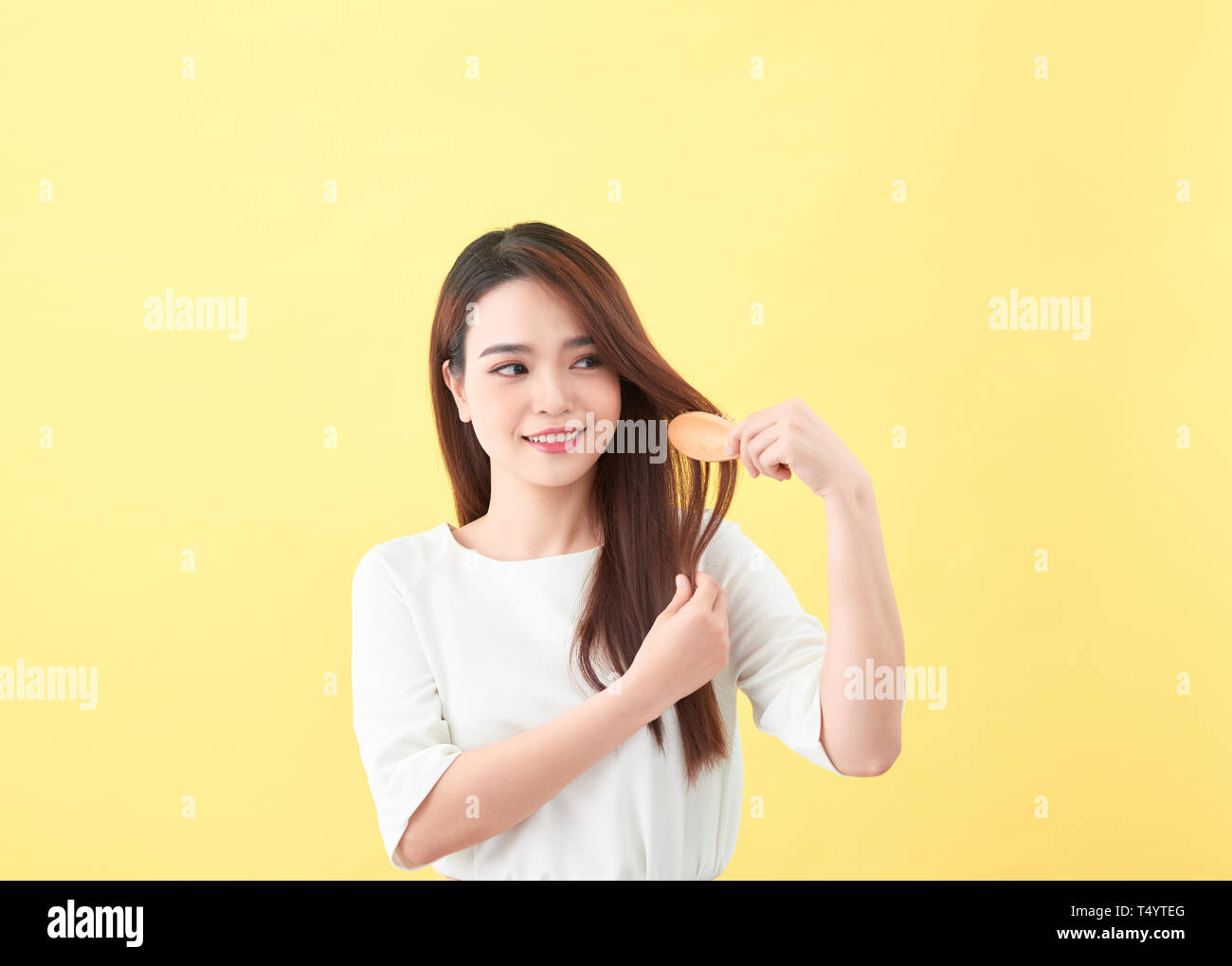 Portrait of beautiful young woman combing her hair and smiling Stock Photo