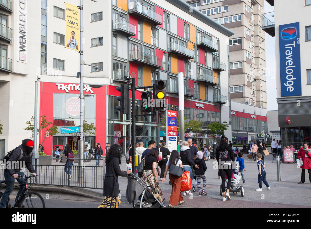 Pedestrians crossing High Road, Wembley, in front of a modern shopping