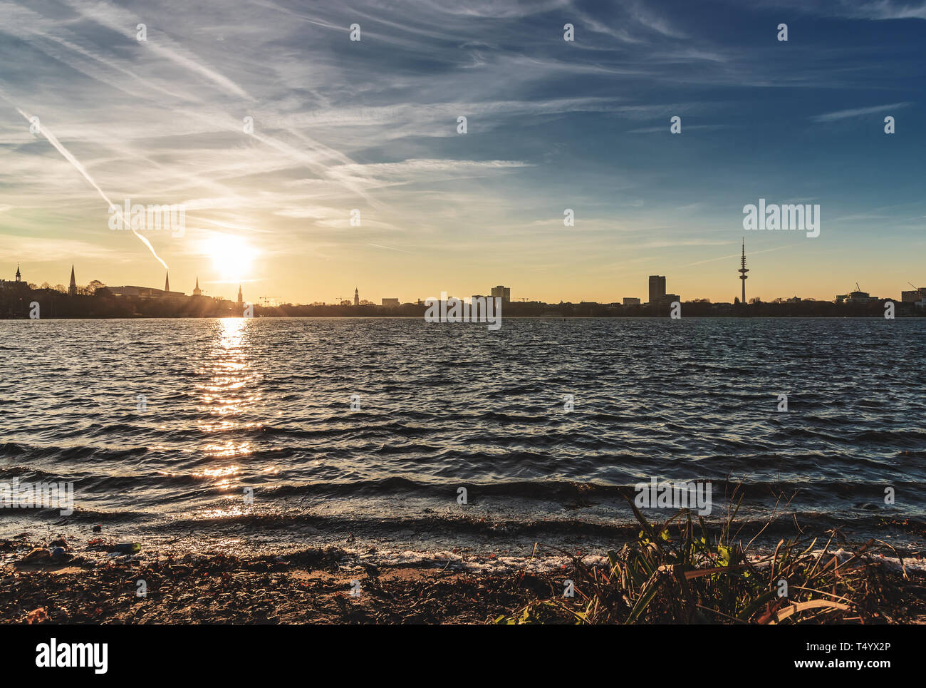 silhouette of Hamburg cityscape as seen from shore of Alster Lake during sunset Stock Photo