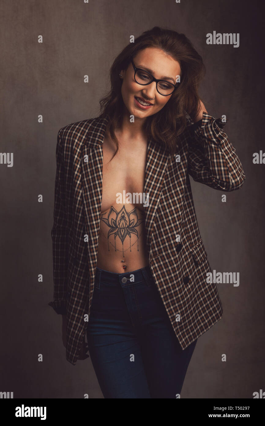 Young woman wearing a jacket with nothing underneath she also has a  tattooed chest. Stock Photo