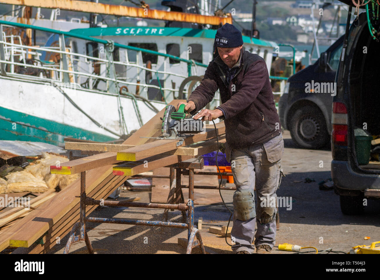 shipwright carpenter cutting a plank of teak wood with an hitachi electric circular saw Stock Photo