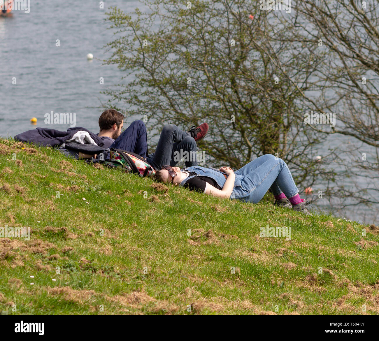 Young couple in a park relaxing in the sunshine by the sea. Stock Photo