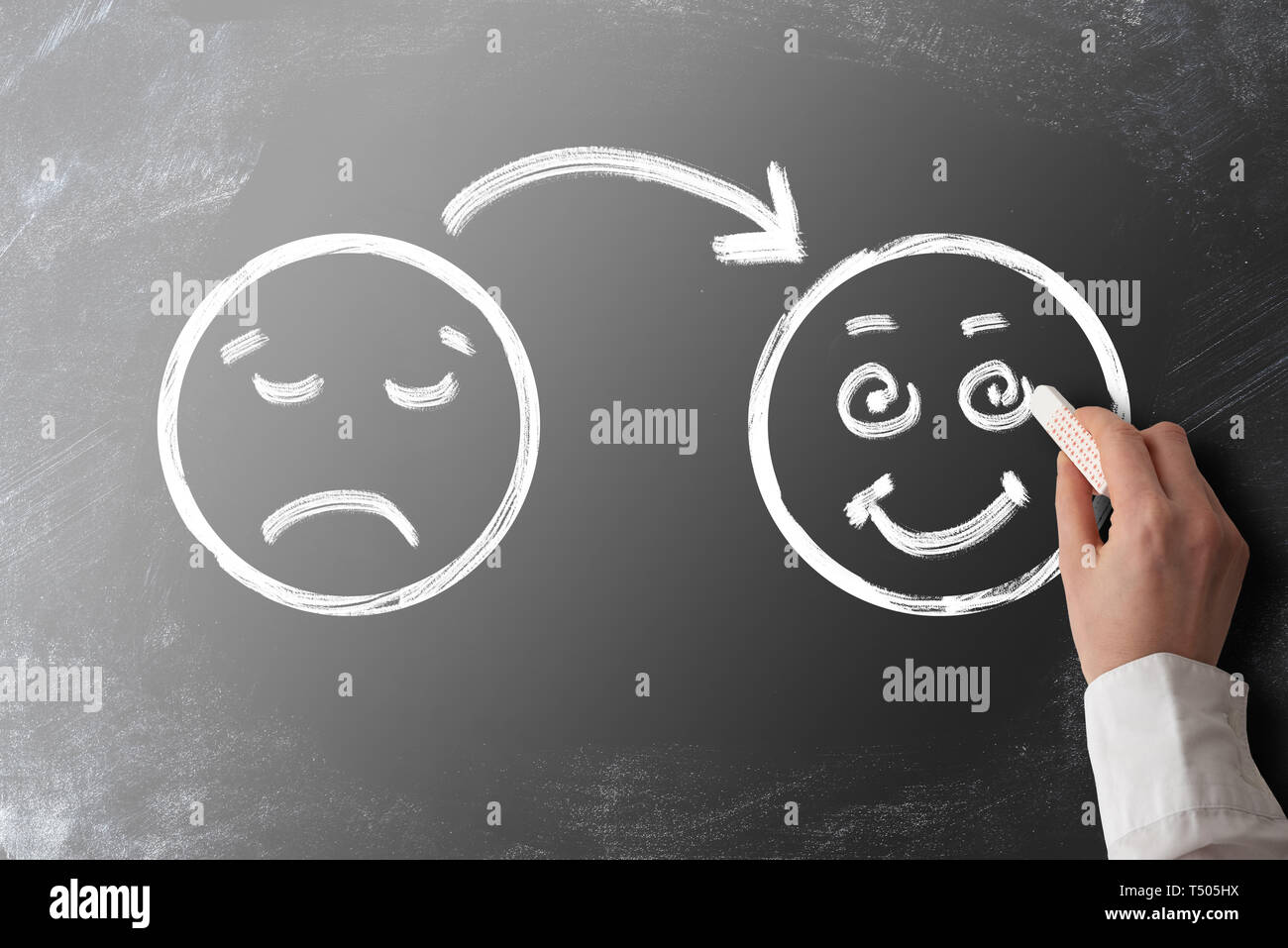 client or customer satisfaction concept with chalk drawing of sad face turning into smiling face on blackboard Stock Photo