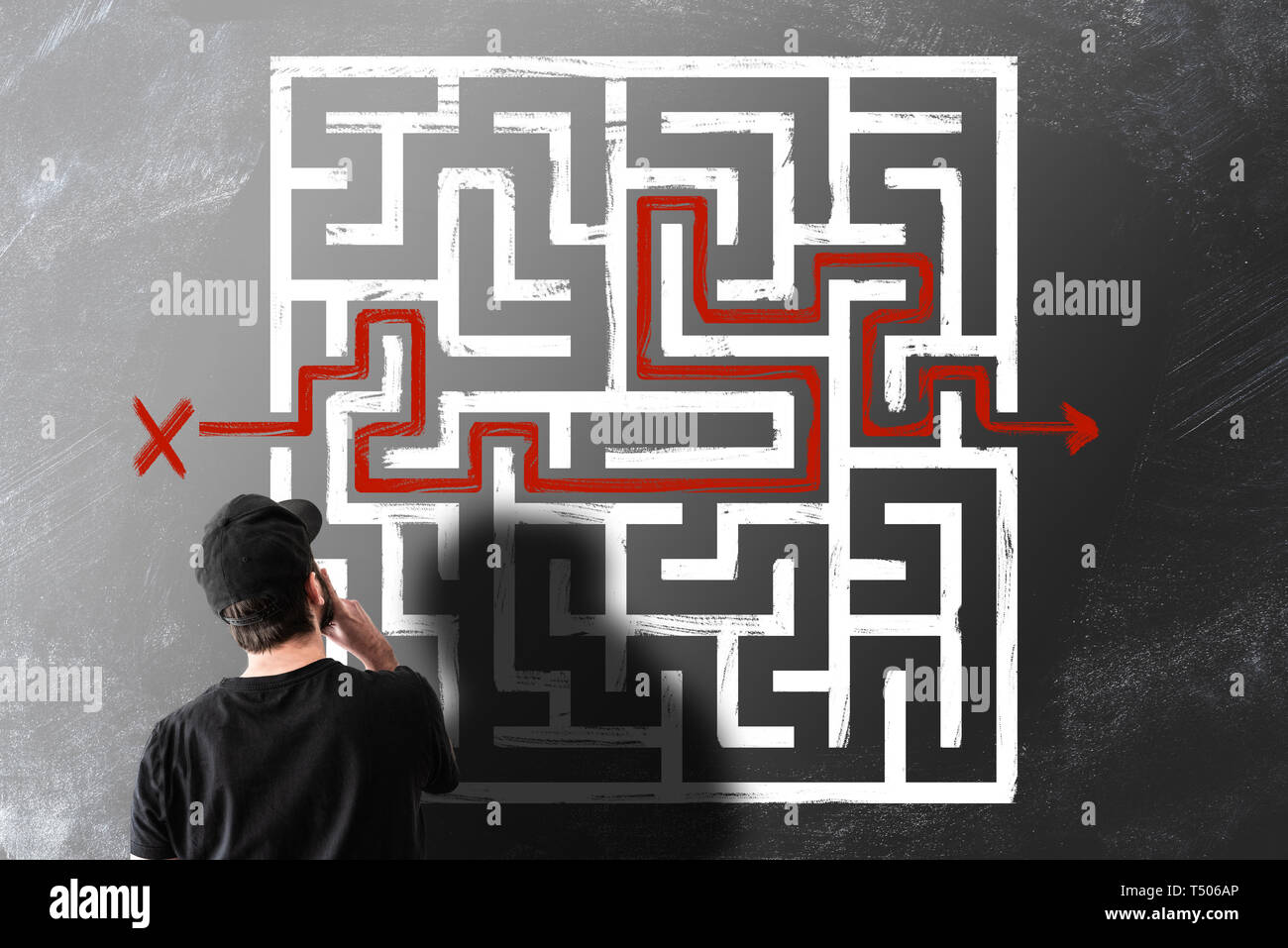 rear view of man looking at chalk drawing of maze labyrinth on blackboard Stock Photo