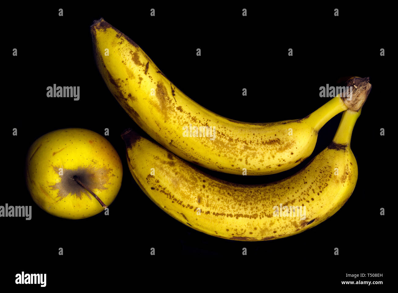 Two ripe banana and apple on a black background Stock Photo