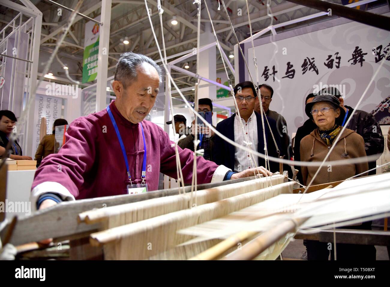 Weifang, China's Shandong Province. 19th Apr, 2019. A folk artist weaves a piece of clothing during the 4th China (Weifang) folk art fair in Weifang, east China's Shandong Province, April 19, 2019. The 4th China (Weifang) folk art fair kicked off here on Friday. More than 50 categories of folk art were displayed and visitors could have a try at the interactive exhibition area. Credit: Guo Xulei/Xinhua/Alamy Live News Stock Photo