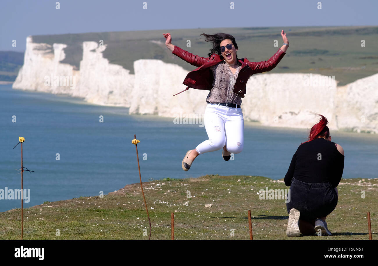 Birling Gap, East Sussex, UK. 20th April 2019. The unseasonably warm weather has seen thousands of tourists flock to the iconic Seven Sisters chalk cliffs near Eastbourne, East Sussex, many of whom take dangerous selfieis on the unstable cliff edge. One man was seen dangling a small child in his arms as he peered over the sheer drop. The cliffs are up to 400 foot high and are a well known suicide spot. © Peter Cripps/Alamy Live News Stock Photo