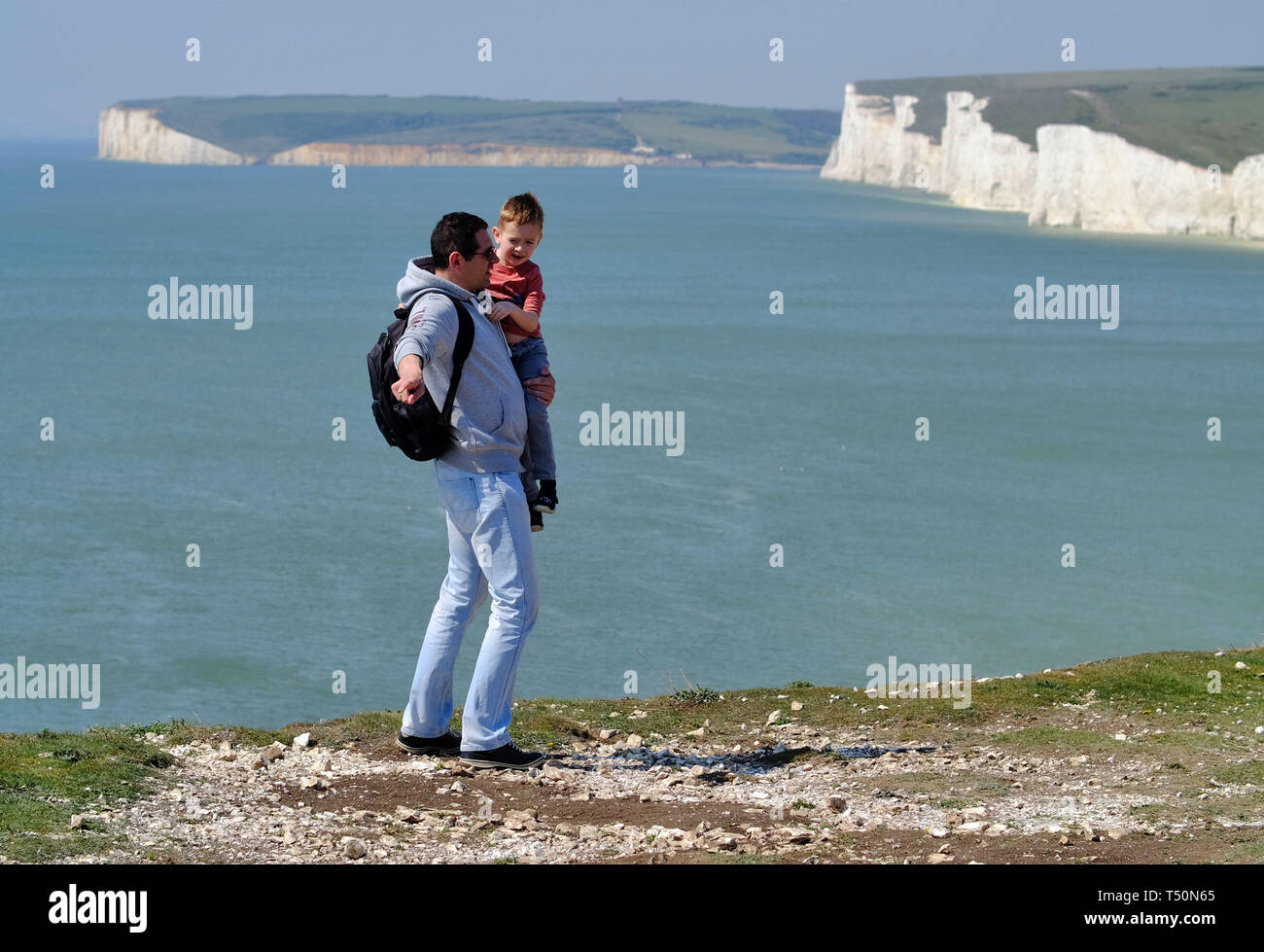 Birling Gap, East Sussex, UK. 20th April 2019. The unseasonably warm weather has seen thousands of tourists flock to the iconic Seven Sisters chalk cliffs near Eastbourne, East Sussex, many of whom take dangerous selfieis on the unstable cliff edge. One man was seen dangling a small child in his arms as he peered over the sheer drop. The cliffs are up to 400 foot high and are a well known suicide spot. © Peter Cripps/Alamy Live News Stock Photo