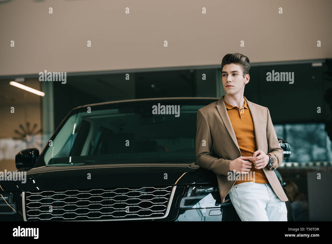 handsome man standing near automobile in car showroom Stock Photo - Alamy