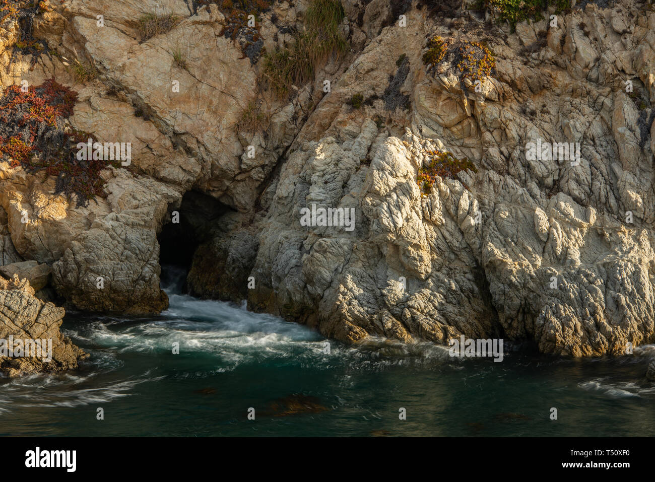 Seaside cliff with swirling water flowing from a cave in Point Lobos State Park on the central coast of California. Stock Photo