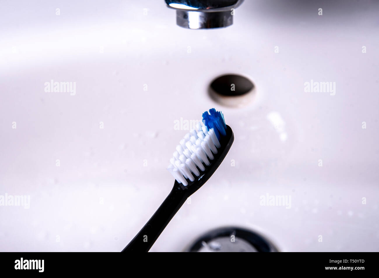 Toothbrush is cleaned in the sink under running water Stock Photo Alamy