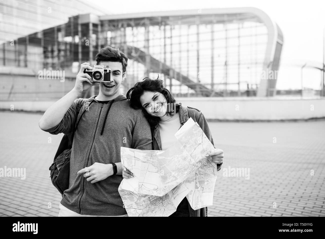 Young cute couple - a boy and a girl walking around the city with a map and camera in their hands Stock Photo