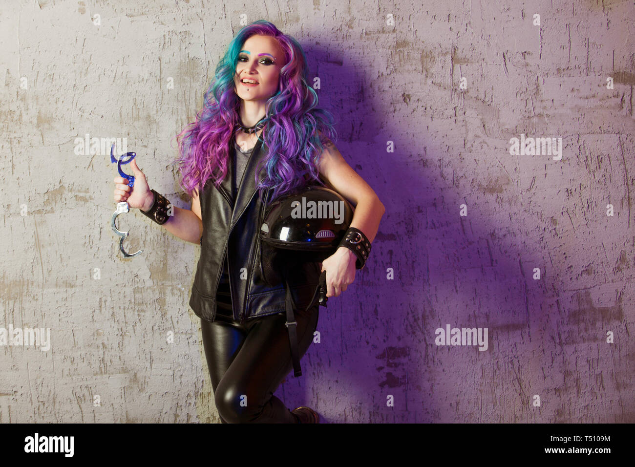 Daring rebel rocker, in black leather clothes with colored hair. Young stylish woman with trendy gradient toning hair, purple and blue. Stock Photo