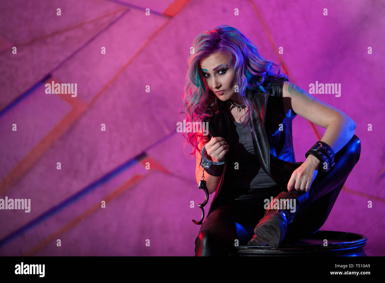 Fashionable young woman in black leather clothes and with colored hair. Bright girl in neon style Stock Photo