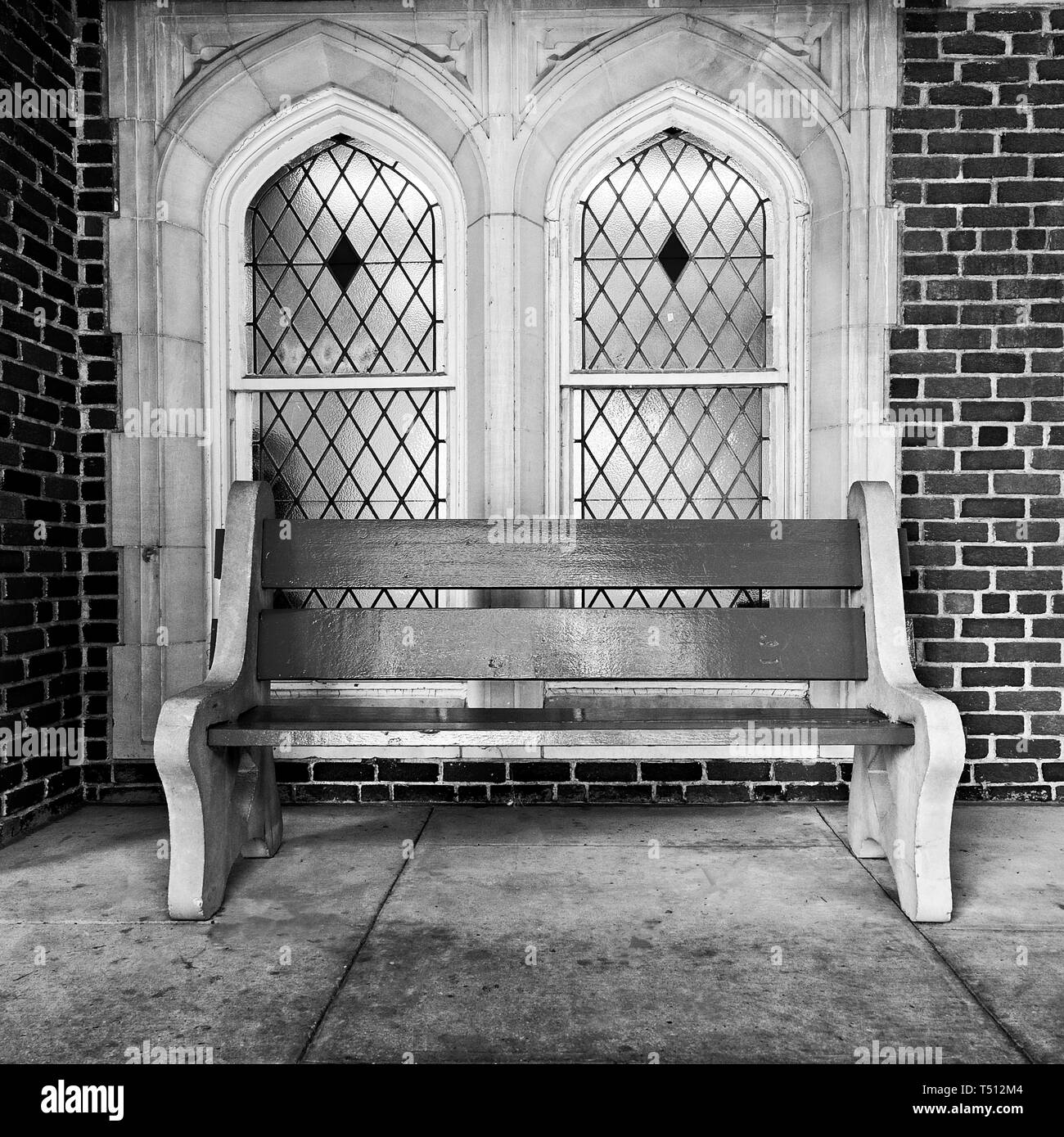 New Orleans, LA USA - 05/08/2018  -  Red Bench In Front of Stained Glass Windows at Loyola University in B&W Stock Photo