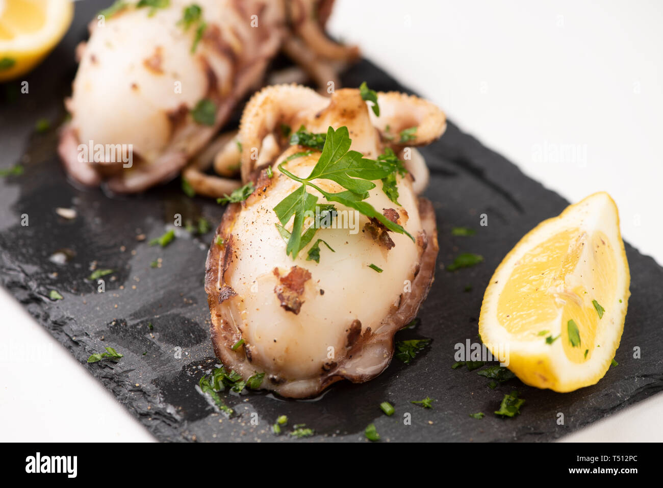 Delicious BBQ cuttle fish on a stone dish isolated on white Stock Photo