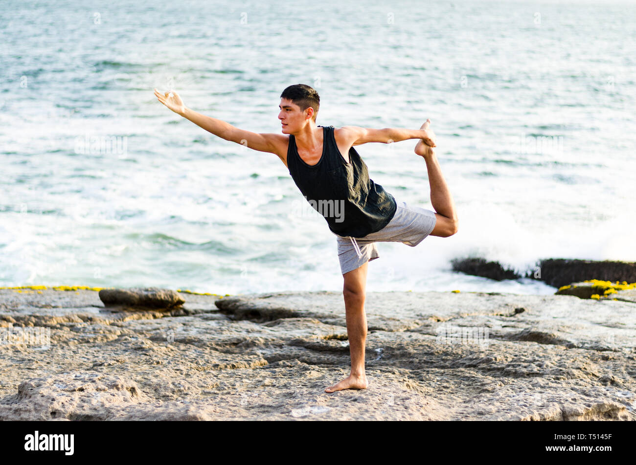 Healthy man practicing yoga. Stretching in natural position in Natarajasana, beautiful sea landscape, sunset, nature, concept for exercise, health care Stock Photo