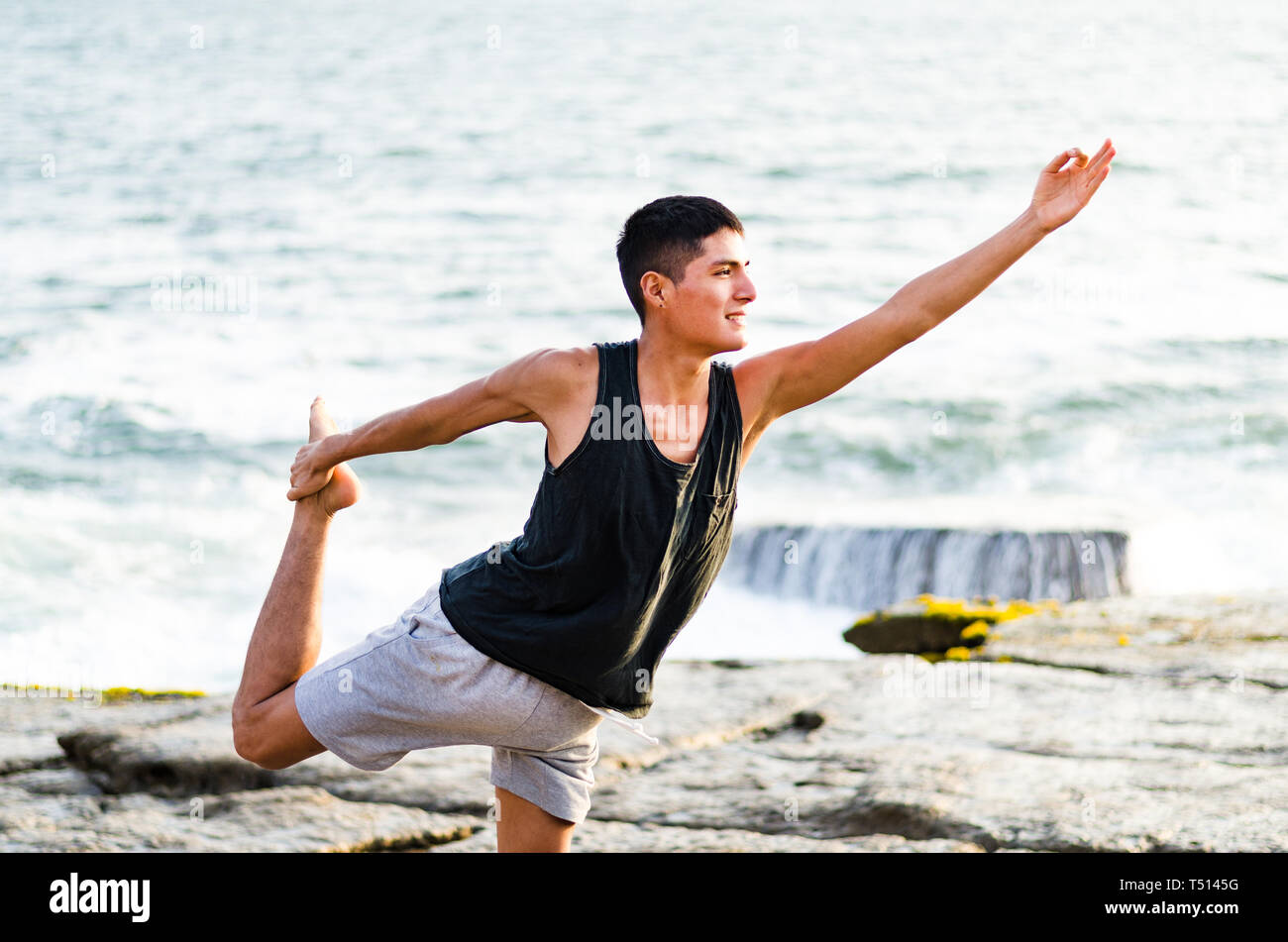 Healthy man practicing yoga. Stretching in natural position in Natarajasana, beautiful sea landscape, sunset, nature, concept for exercise, health care Stock Photo