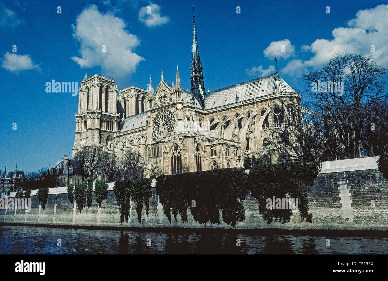A view from the River Seine of the gothic Notre-Dame de Paris, the famous Catholic cathedral in the French capital that is one of Europe's most popular tourist attractions. This photograph was taken before the historic church suffered major damage by a disastrous fire in April, 2019, and was closed for restoration. Construction of the ancient stone structure began in the 12th Century and featured ornate medieval architecture that included twin bell towers, stained-glass rose windows, flying support buttresses and the soaring wooden central spire (that was destroyed in the fire). Stock Photo