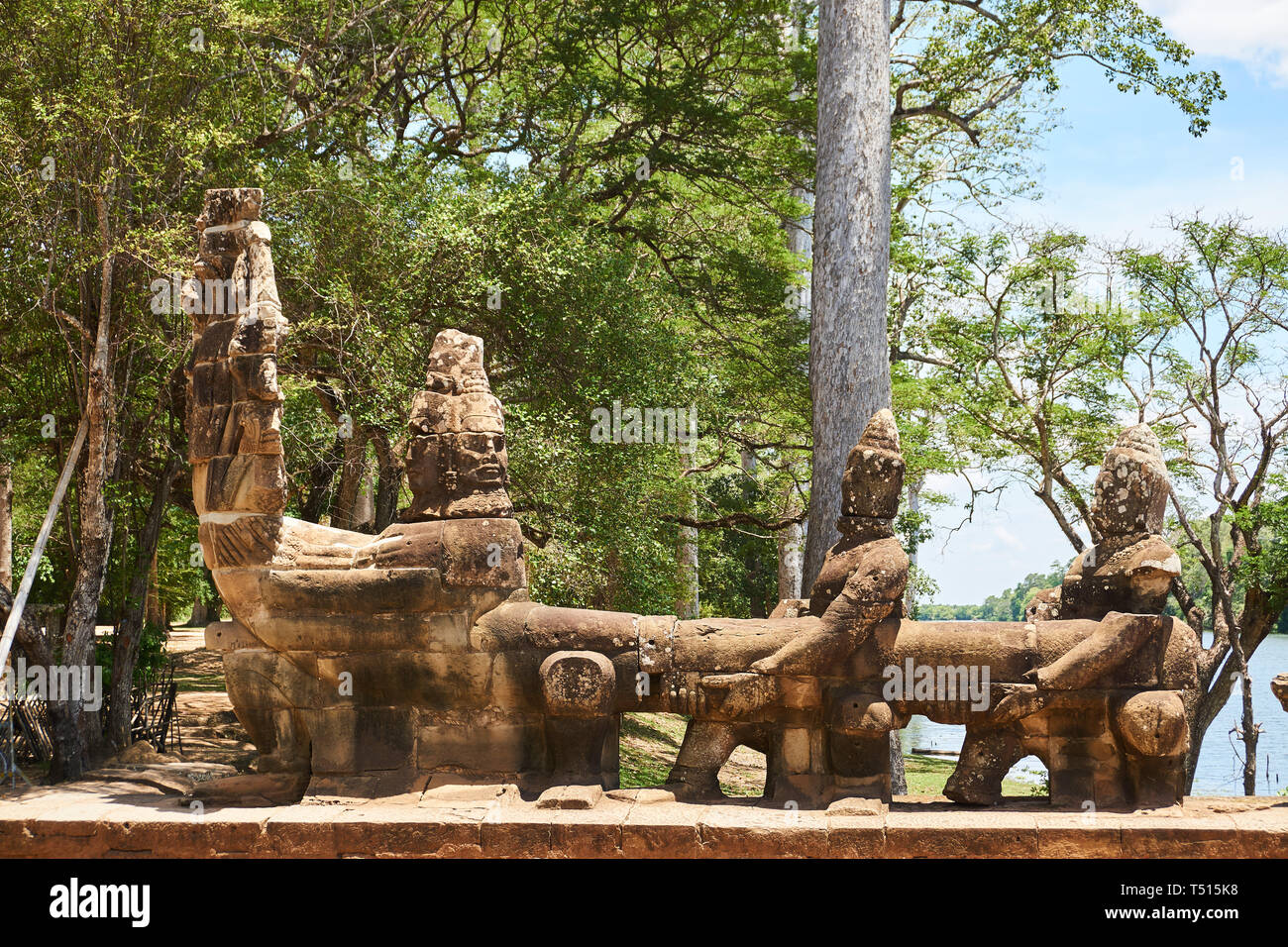 Sandstone deva statues holding the body of a nine-headed Naga king Shesha, south gate of Angkor Thom in the Angkor Archaeological Park, Cambodia. Stock Photo