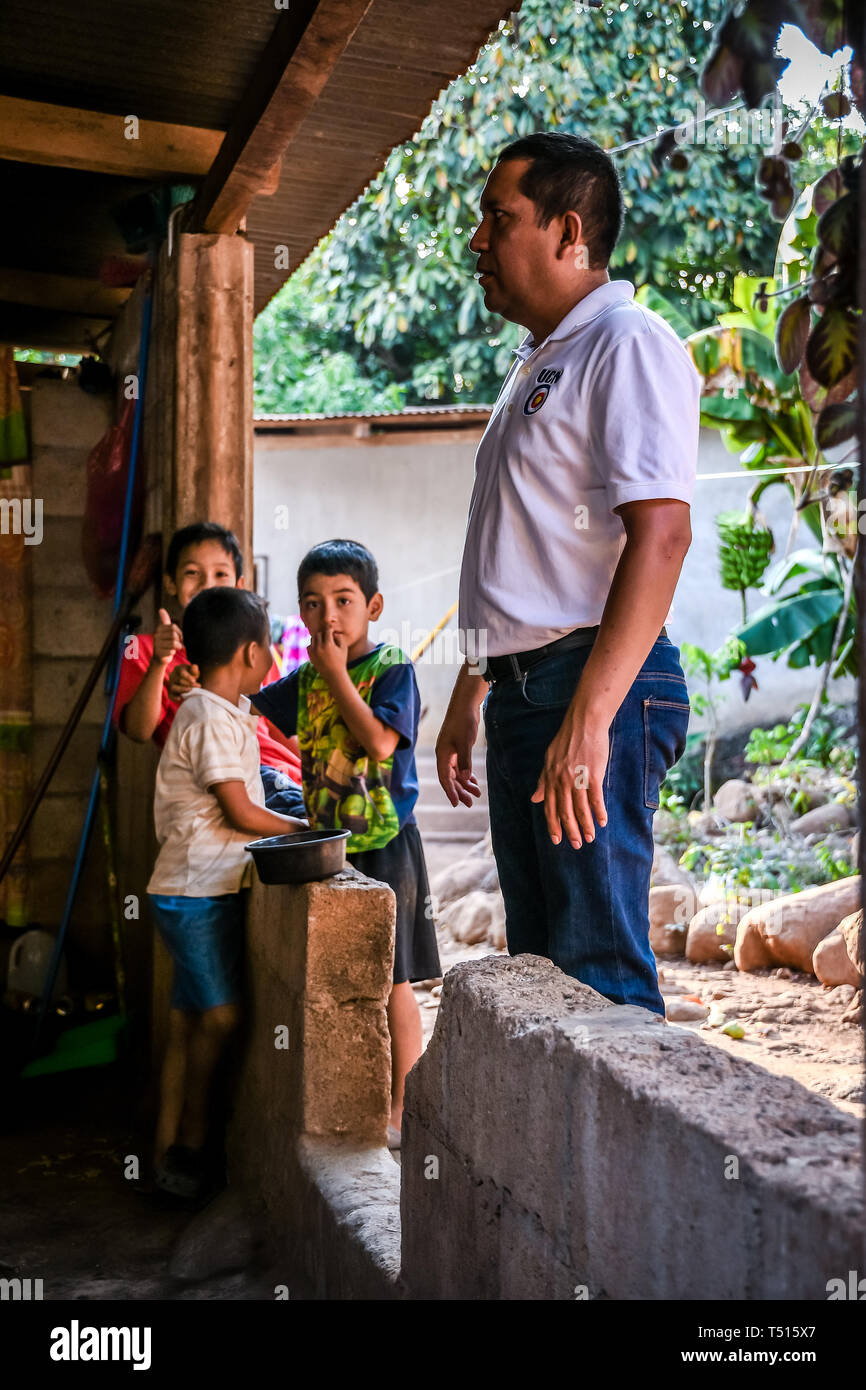 latin man standing with children in background in Guatemalan house Stock Photo