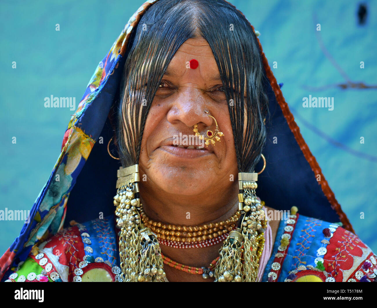 Elderly Indian Banjara tribal woman from Karnataka wears nose jewelry, embroidered tribal garment and headscarf with buttons, shiny discs and beads. Stock Photo