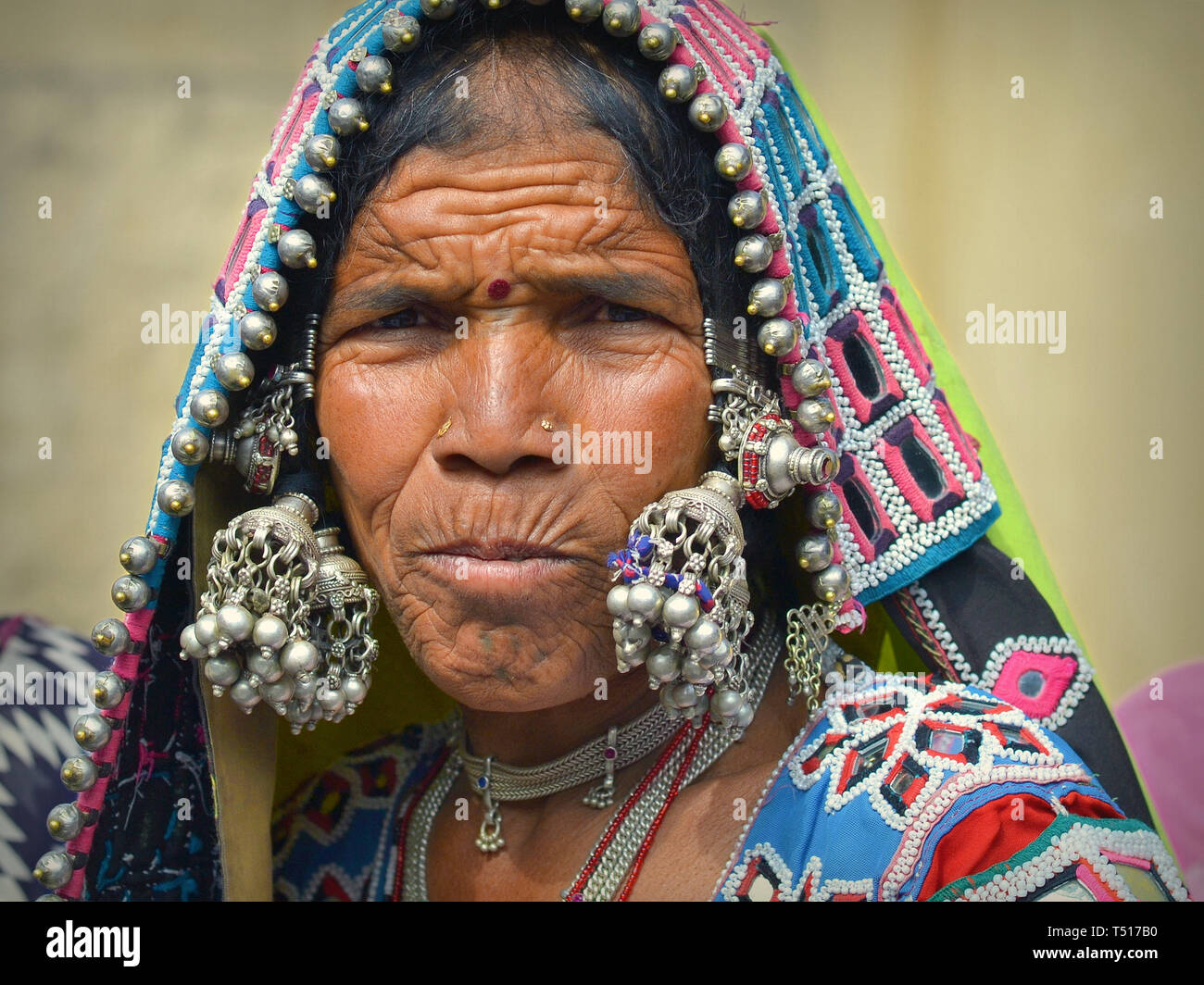 Elderly Indian Banjara tribal woman wears her intricately embroidered,  colourful tribal garment and headscarf with innumerable silver balls and  bells Stock Photo - Alamy