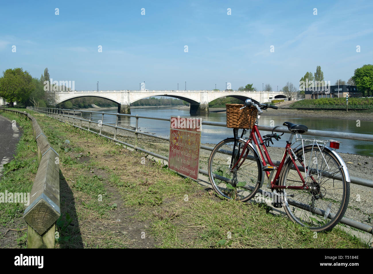 bicycle parked on railings beside the river thames in mortlake, with chiswick bridge in background Stock Photo