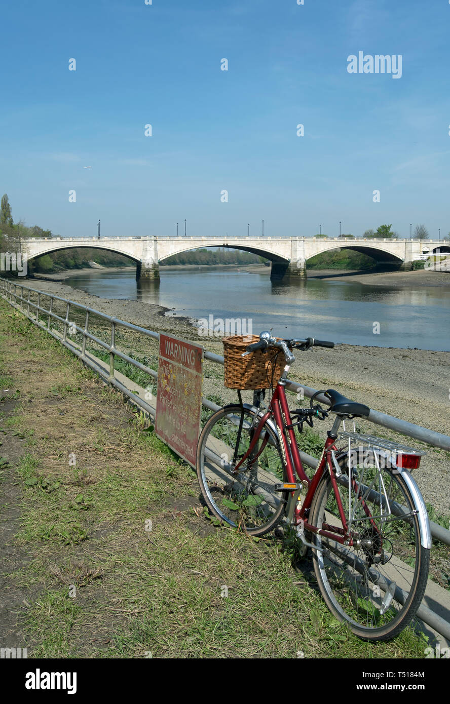 bicycle parked on railings beside the river thames in mortlake, with chiswick bridge in background Stock Photo