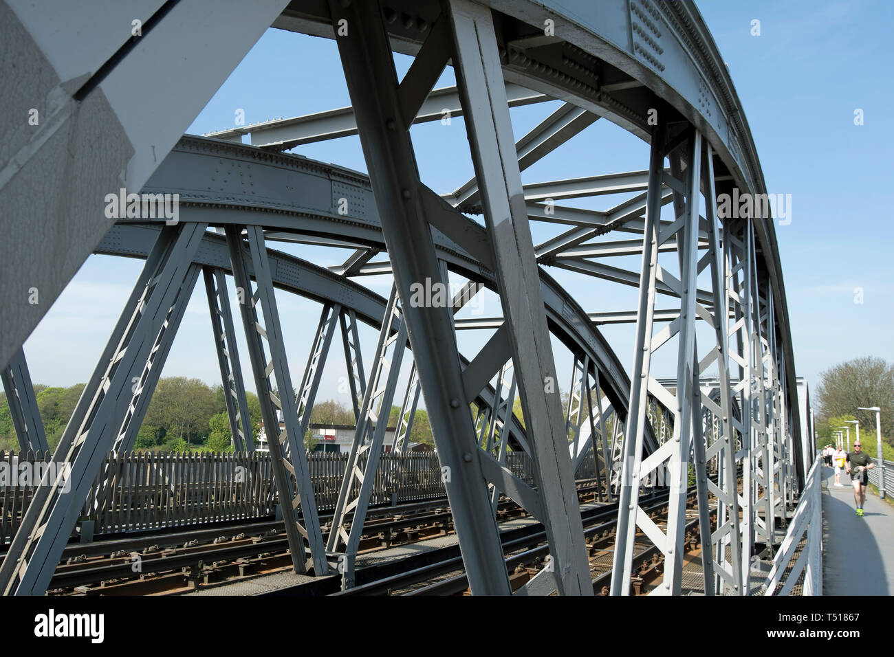 male jogger on a footway is dwarfed by the steel girders of barnes rail bridge, barnes, london, england Stock Photo