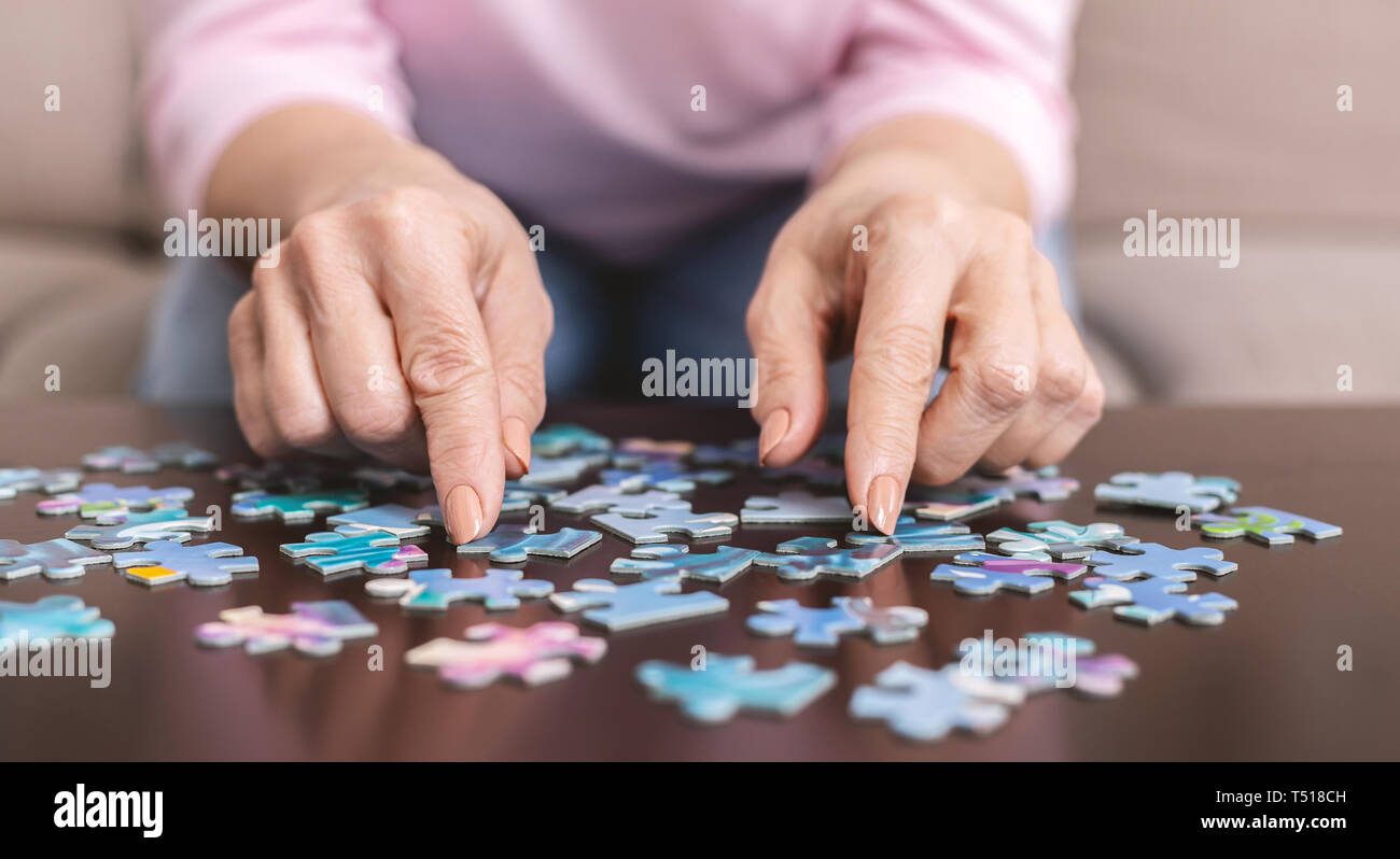 Elderly woman hands doing jigsaw puzzle closeup Stock Photo