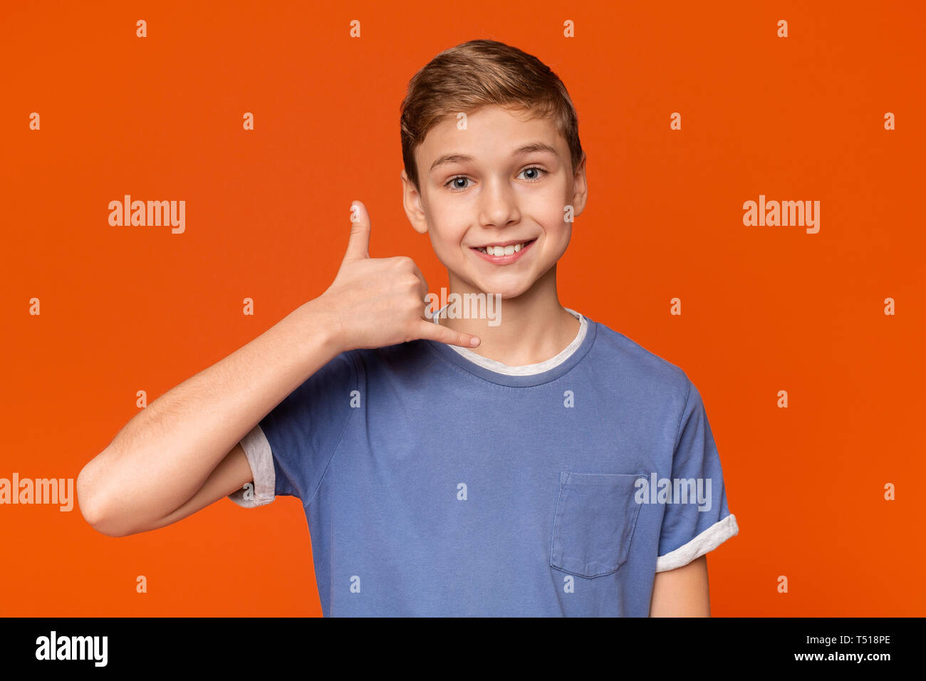 Cute boy put his hand to his ear and smiling Stock Photo
