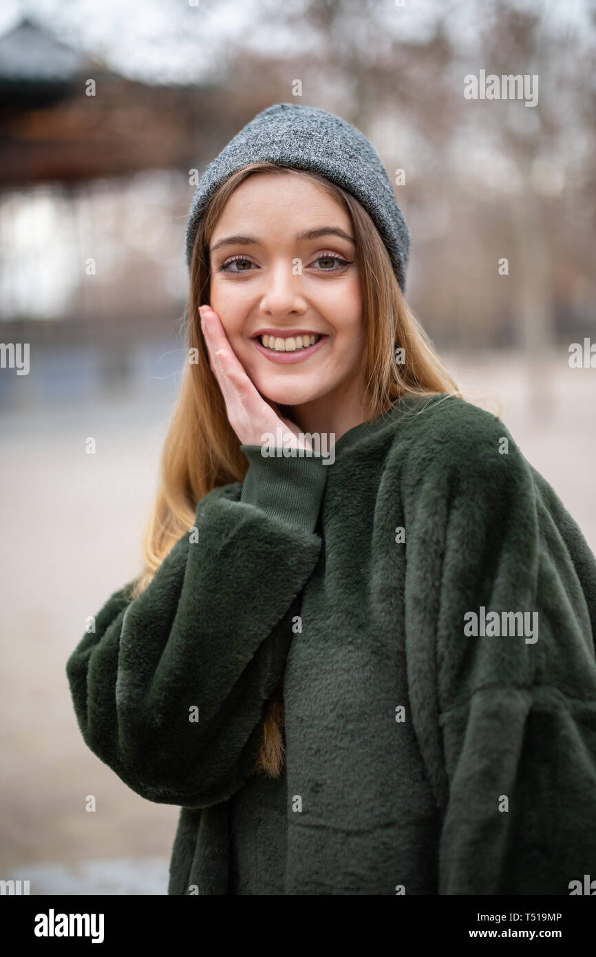 Portrait of happy smiling young blond woman with winter hat in a park in autumn Stock Photo