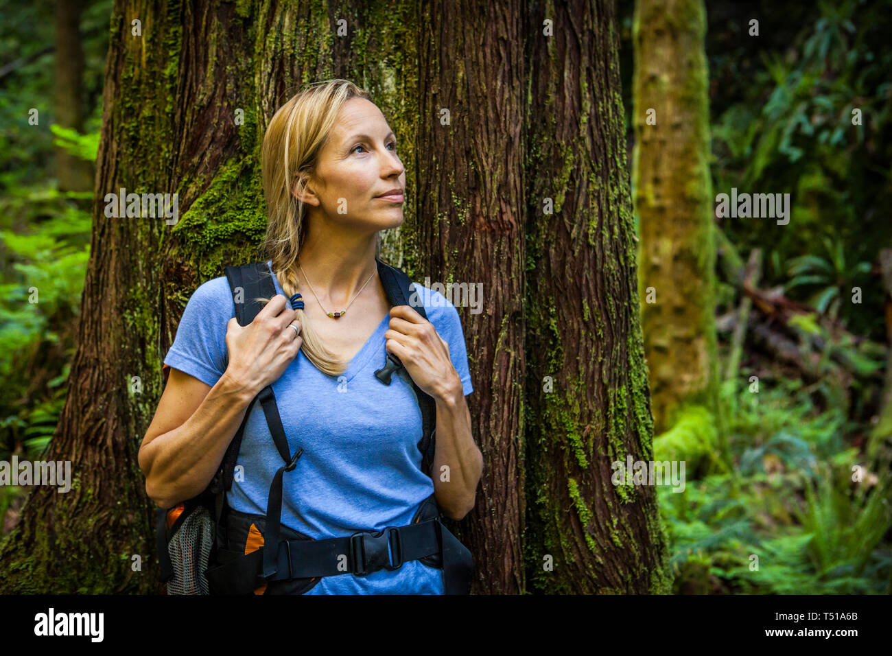 A portrait of a Caucasian woman in front of a large tree in the forest, Little Si trail, Washington. Stock Photo